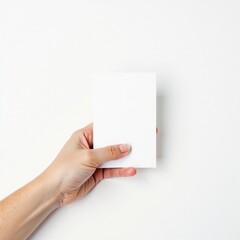 A hand holds a blank white card against a white background.  Perfect for mockups and presentations, this image offers clean, simple design.