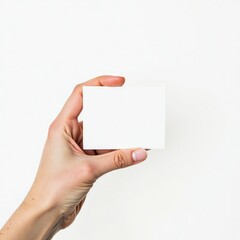 Obraz premium A hand holding a blank white card against a white background. Perfect for mockups or presentations.