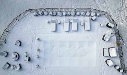 snow covered lounge chairs surrounding a shuttered swimming pool in winter (looking down aerial)...