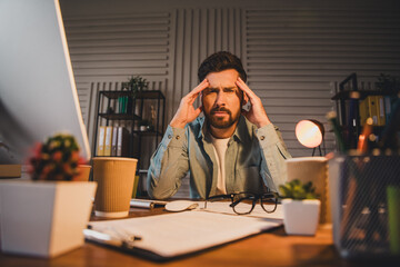 Young businessman feeling stressed while working late at his home office desk
