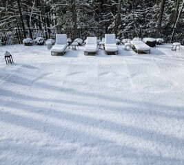 snow covered lounge chairs surrounding a shuttered swimming pool in winter (looking down aerial) back yard patio blizzard snowy weather outdoor furniture cover covered in ground built in off season 