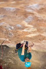 A man is climbing a rock wall with a rope and harness