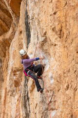 Obraz premium A woman is climbing a rock wall with a rope