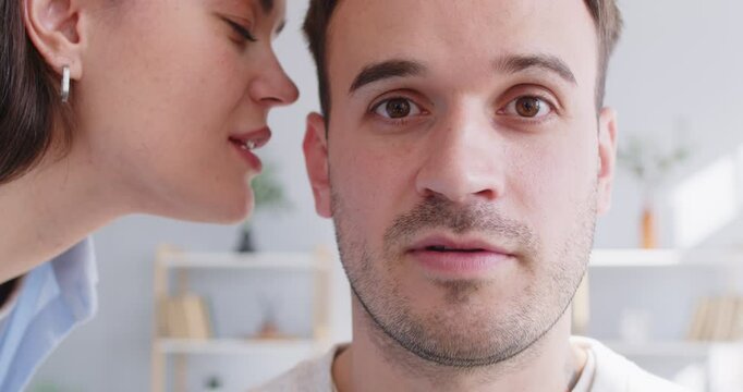 Woman whispering in a man's ear. Closeup happy young man in love who smiles as his girlfriend tells about a secret nice pleasant private surprise that he is sure to like. Couple relationship concept