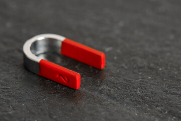 One horseshoe magnet on dark textured table, closeup. Space for text