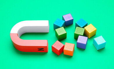 Magnet attracting colorful cubes on green background