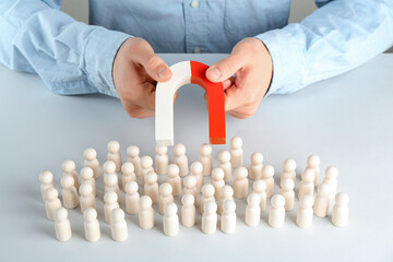 Man with magnet attracting game pieces at white table, closeup