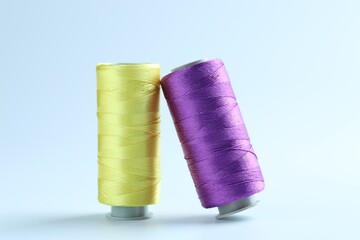 Spools of colorful sewing threads on light background