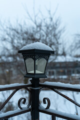 A snow-covered landscape features a streetlight on a fence, surrounded by a blanket of snow. This winter scene captures the calm and quiet of a snowy day