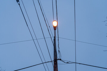 A symmetrical shot of a streetlight against the evening sky, framed by electrical wires. This minimalistic winter scene captures the beauty of urban elements in a serene and tranquil setting.