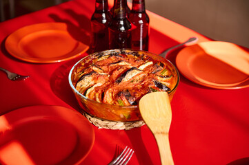 Rustic baked ratatouille served on a vibrant table with red plates