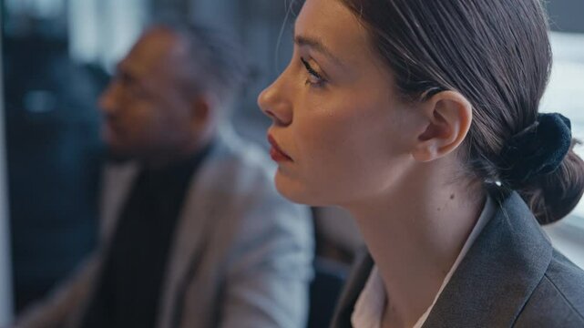 Close-up of a thoughtful businesswoman nodding during a meeting, with a blurred colleague in the background. Concept of workplace collaboration, professional communication, and focus