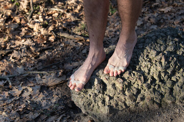 Standing barefoot on a rugged surface, the silicone separator between the toes offers a unique blend of comfort and support. Natural surroundings enhance the outdoor experience