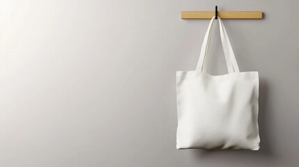 White tote bag hanging on wall, grey background, mockup