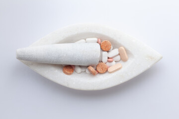 Health care concept. Close-up of Medical Pills and Tablets, in a white marble mortar and pestle, isolated on a white background.