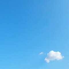 A clear blue summer sky with a few small wispy white clouds drifting lazily across it, natural, peaceful, warm