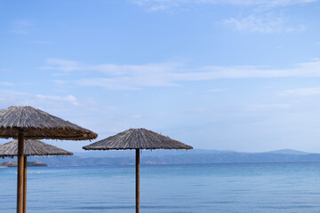 straw umbrellas on the background of the horizon line on the sea coast
