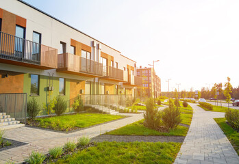 Sidewalk with green lawn at Modern Townhouse. Pedestrian path with flowerbed shrubs. Townhouse in suburb. Modern building in green enviroment. Street with Two-story townhouses in Gated Community.