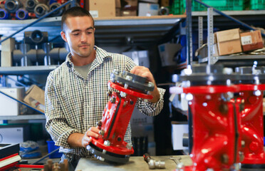 Caucasian man mechanic assembling plumbing fixture in workshop.