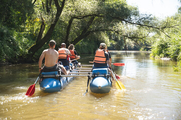 a team of athletes on a catamaran overcomes obstacles floating on the river © Tsyb Oleh