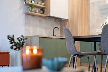 Modern kitchen interior with wooden furniture and counter with kitchen sink. Beige tiles on the wall and table with chairs. Design home with dining room. Real estate.	