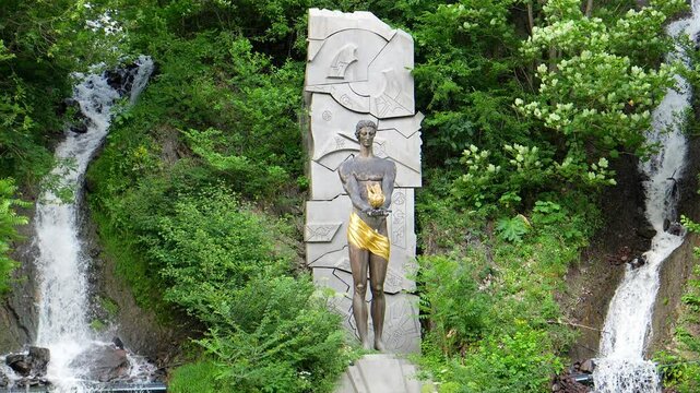 Monument to Prometheus at waterfall in Borjomi, Georgia. depicts statue of god, surrounded by lush vegetation