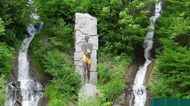 Monument to Prometheus at waterfall in Borjomi, Georgia. depicts statue of god, surrounded by lush vegetation