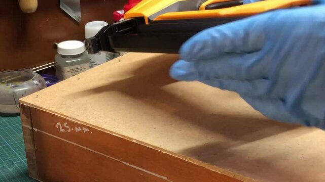 electric stapler, nailer in the hands of a person hammering nails into a box