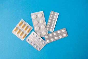 Different blisters with pills lie on blue background, space for text