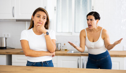 Offended woman listening her girlfriend standing behind and quarreling with her
