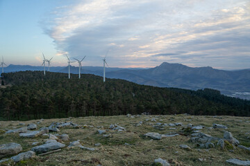 eolic generators spinning in a windy hill at sunset