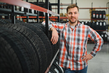 Portrait young man customer examining brand and product characteristics while buying new tires in...