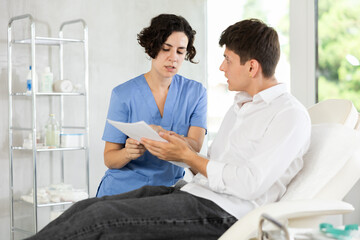 Obraz premium Male patient signs the contract for the operation in the clinic of body aesthetics