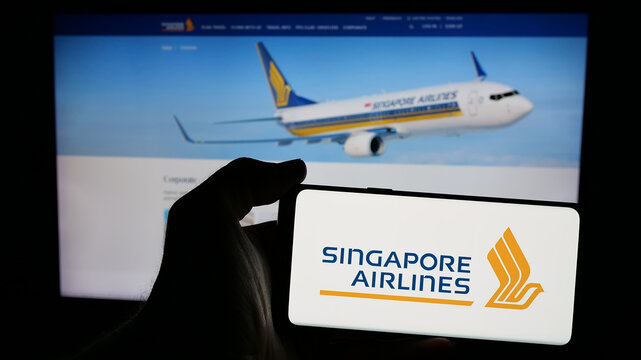 Stuttgart, Germany - 01-20-2025: Person holding mobile phone with logo of airline company Singapore Airlines Limited on screen in front of business web page. Focus on phone display.