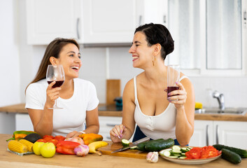 Happy carefree young latin american lesbian couple chatting carelessly and drinking wine while...