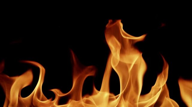 Beautiful dancing fire, the surface is ablaze. Lots of fire. Close-up immersion in the flames. The camera passes through the fire. Burning tongues of flame on a black backdrop in slow motion. 4K.
