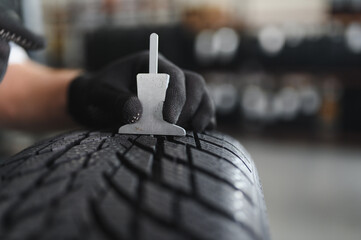 A professional worker in a car service measures the tread diameter of a wheel with a special tool. Concept of Car safety, Special uniform, Diameter, New tires