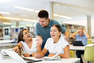 Fototapeta premium Friendly happy group of students preparing together for exam in modern university library