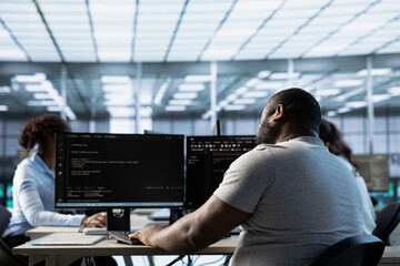 Data center employee using PC to find misconfigurations affecting rackmounts performance. Man checking servers bottlenecks leading to sluggish data transfer rates and malfunctions