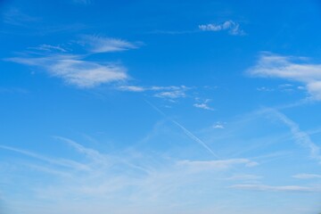 Experience the serene beauty of a clear blue sky with soft, wispy white clouds. This stunning image...