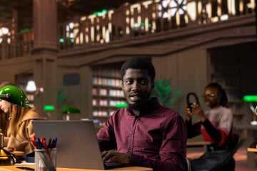 Black male student collecting academic information from the campus library, doing research to help with exam preparations. Young pupil with an education opportunity fights for a certificate.