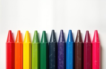 Colorful crayons arranged in row against white background. Variety of vibrant colours create spectrum of hues. Childrens art supplies displayed close up. Isolated object against plain background.