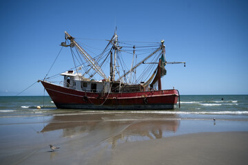 Stranded Fishing Boat on a Sandy Shore Under Clear Blue Skies