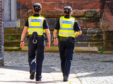 Policewomen walk the street in United Kingdom.