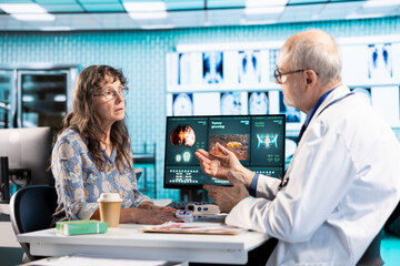 Medical expert using professional tool to take oxygen levels saturation at examination, using oximeter on finger and consulting old woman at clinic. Medic does pulse rate measurement.