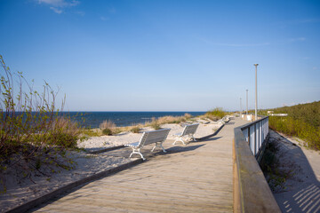 Wooden Boardwalk with Benches Overlooking the Sea in Dziwnów © Robert