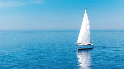 Fototapeta premium Sailboat sailing on calm blue sea under sunny sky; travel and leisure imagery