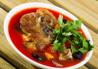Savory tomato soup with mutton meat, vegetables, dried plums and apricots served with greens
