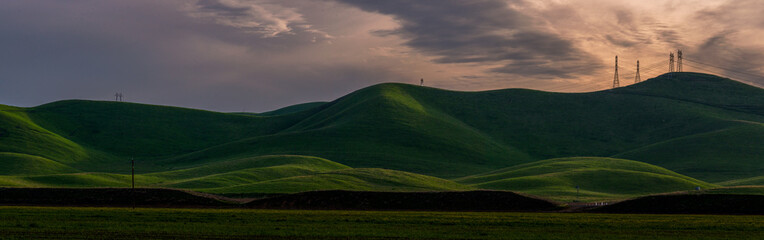 Obraz premium Power Lines on top of green rolling hills