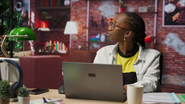 Fatigued teleworker feeling overworked, taking break after working too much on job tasks. Exhausted woman at home pausing work to relax and regain energy, looking out the window, camera B